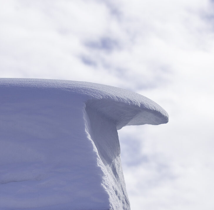 A sculpture made of snow and wind hangs over a rooftop