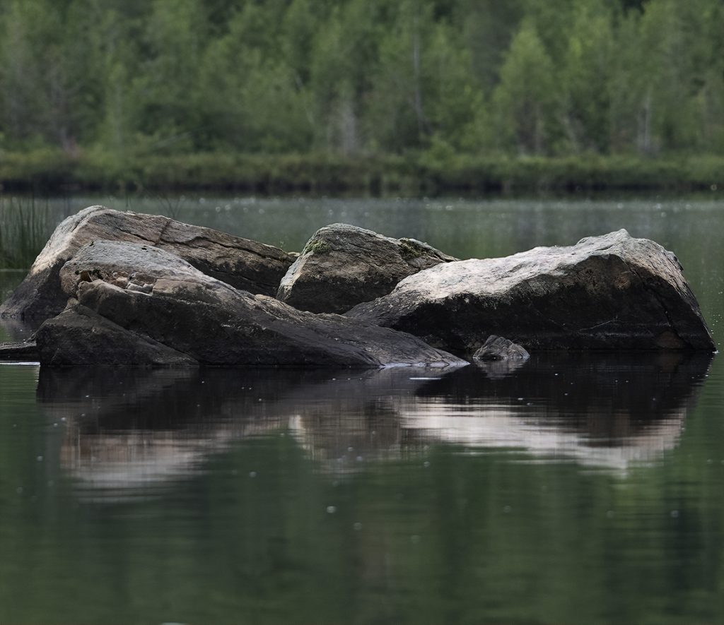 Two boulders seemingly intertwined with a combined reflection that looks like an infinity symbol