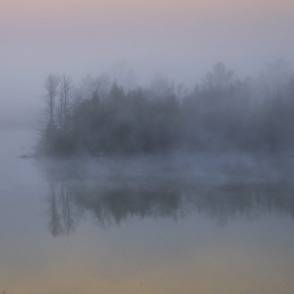 Ice fog settles in over a lake in the November dawn